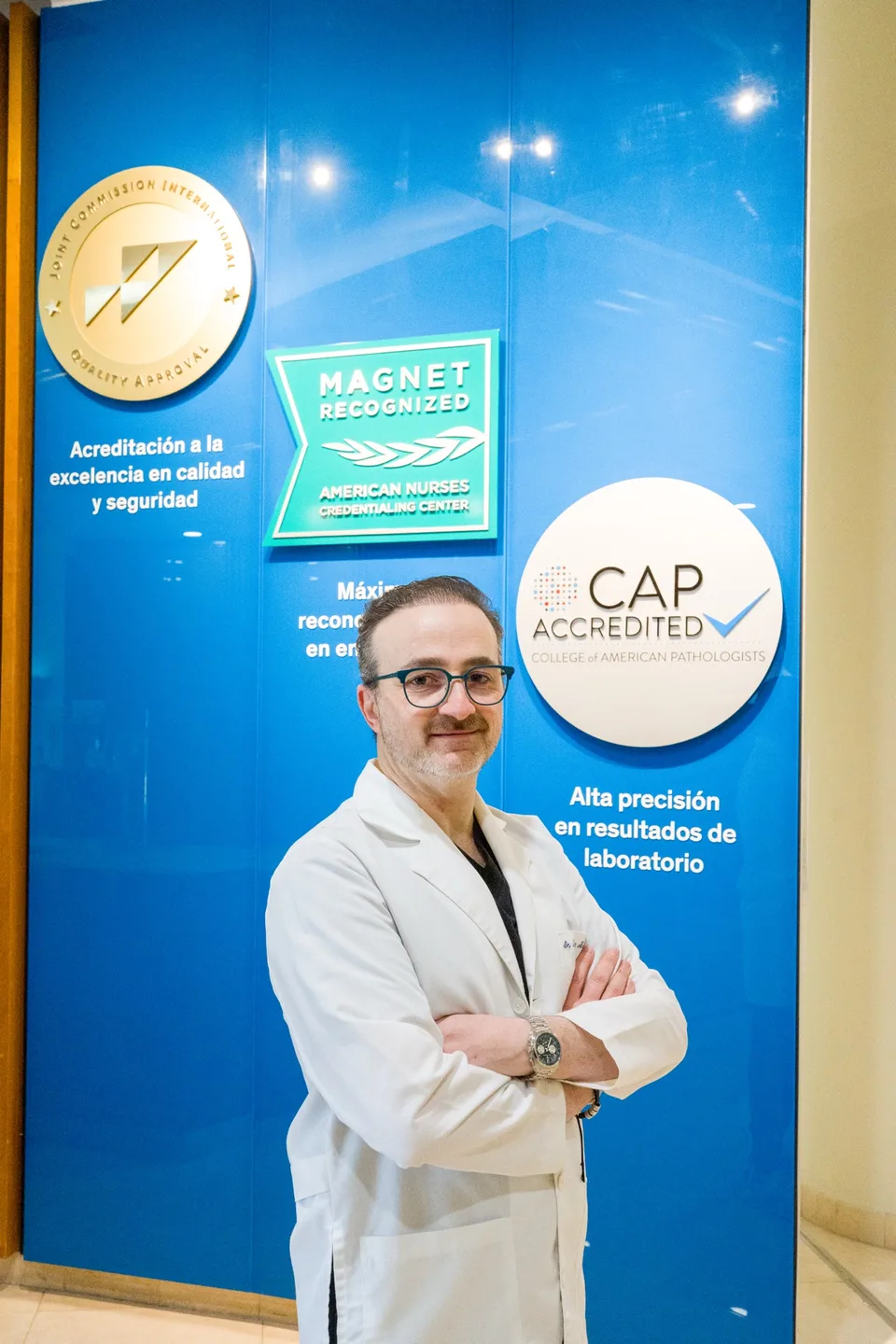 Dr. Isaac Baley beside the hospital accreditation wall